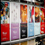 Row of advertisement posters on a wall with various brands and products.